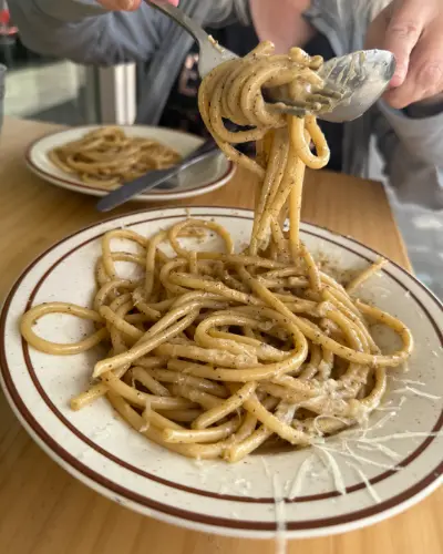 A fork twirling spaghetti cacio e pepe above the bowl